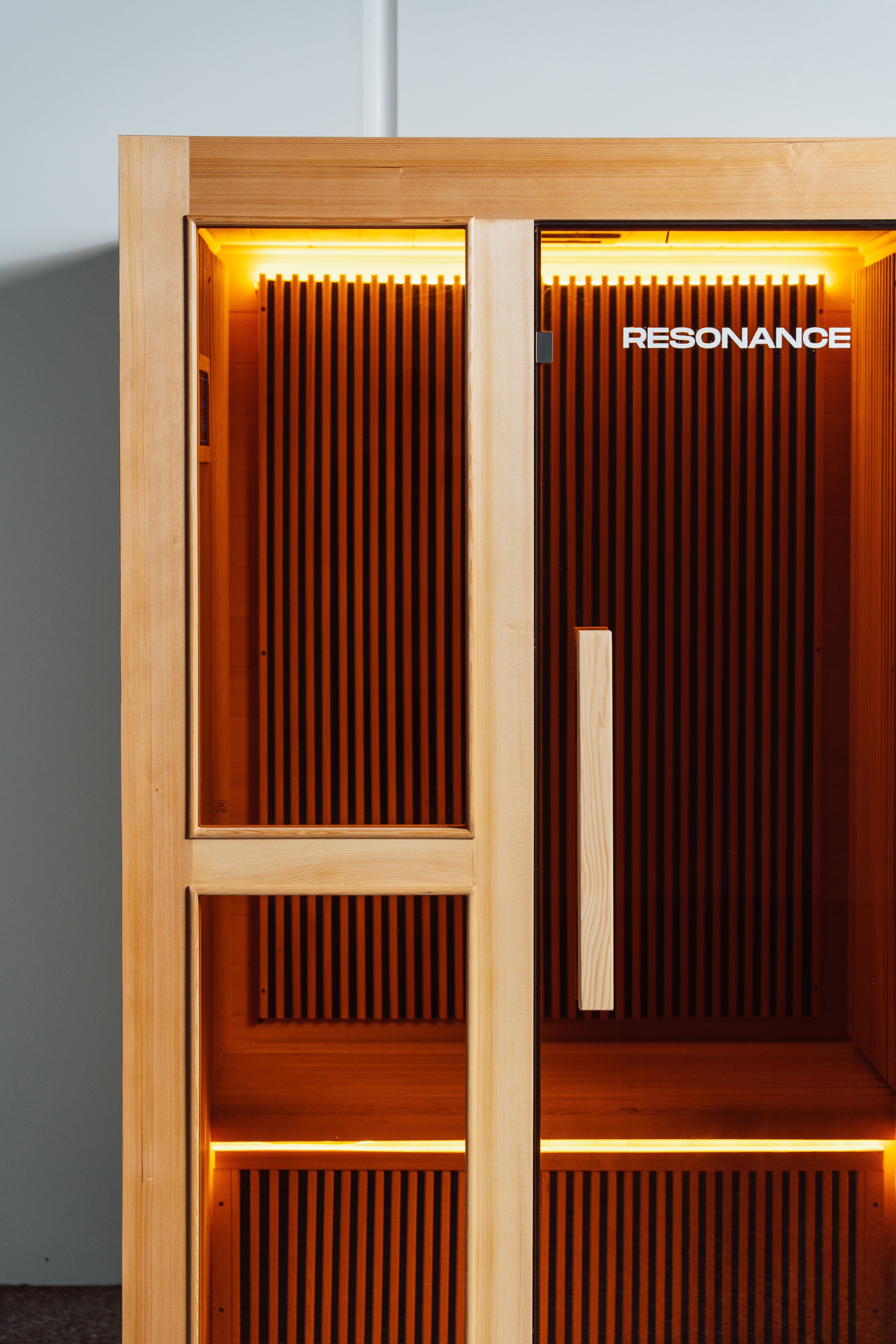 Recovery Pod interior view through open door — full-spectrum infrared cedar panels and chromotherapy lighting
