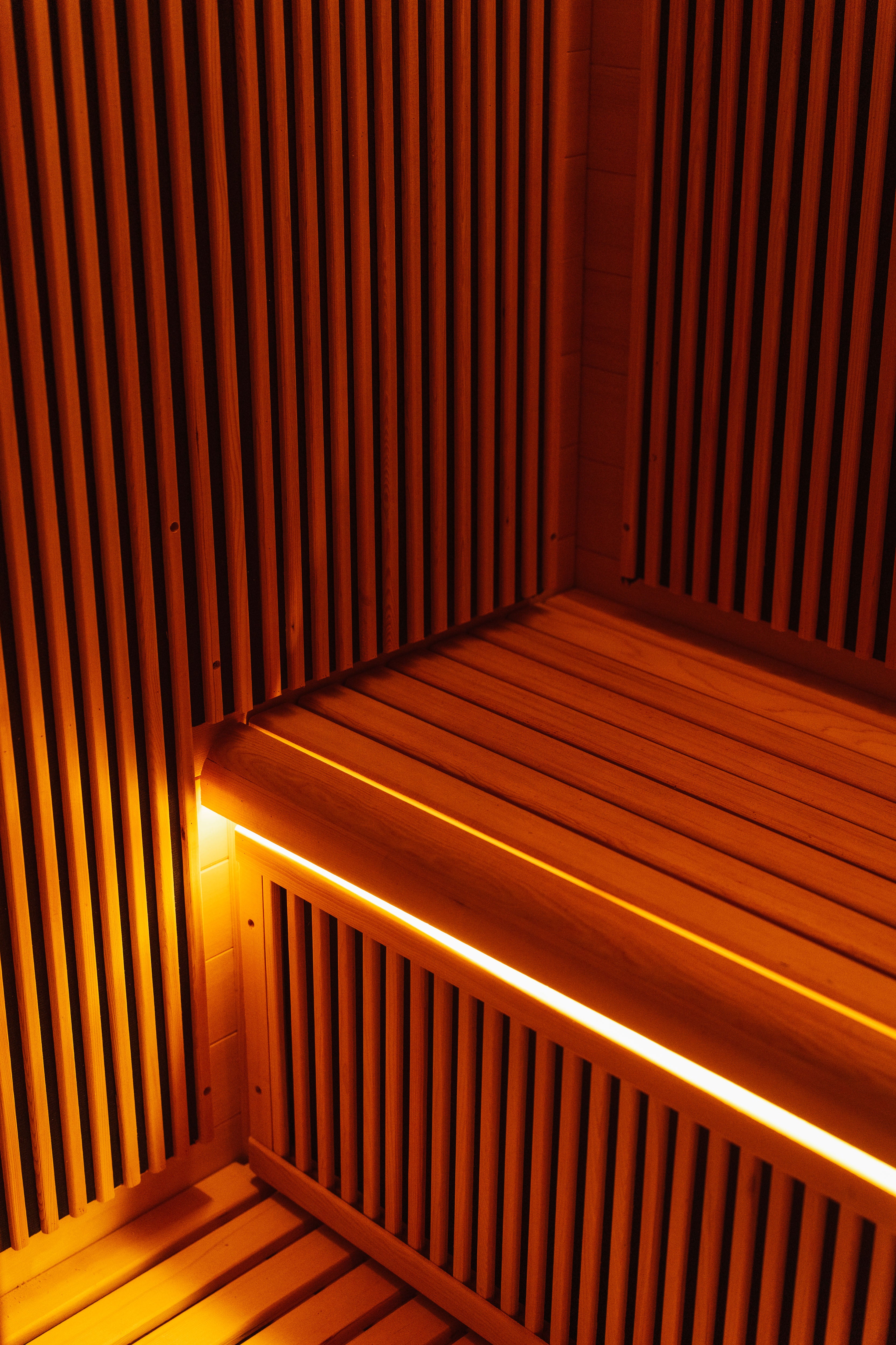 Recovery Pod interior cedar bench close-up with warm under-bench infrared heater lighting